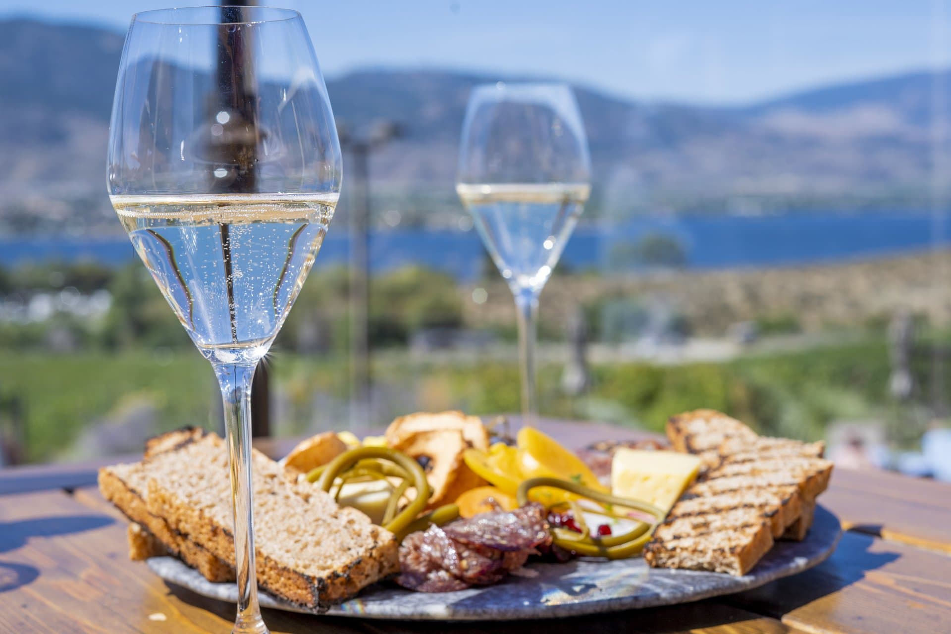 A charcuterie board and sparkling wine on a patio overlooking Osoyoos Lake