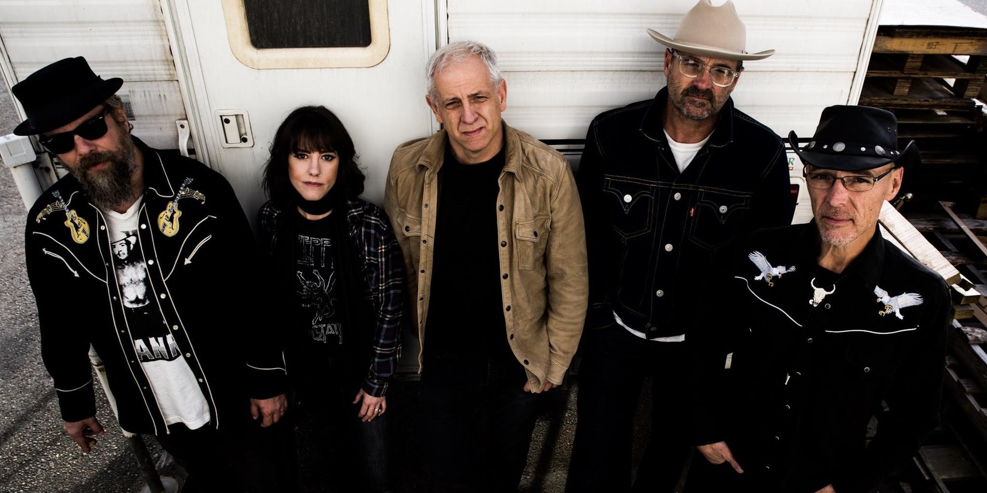 five band members posing in front of an RV