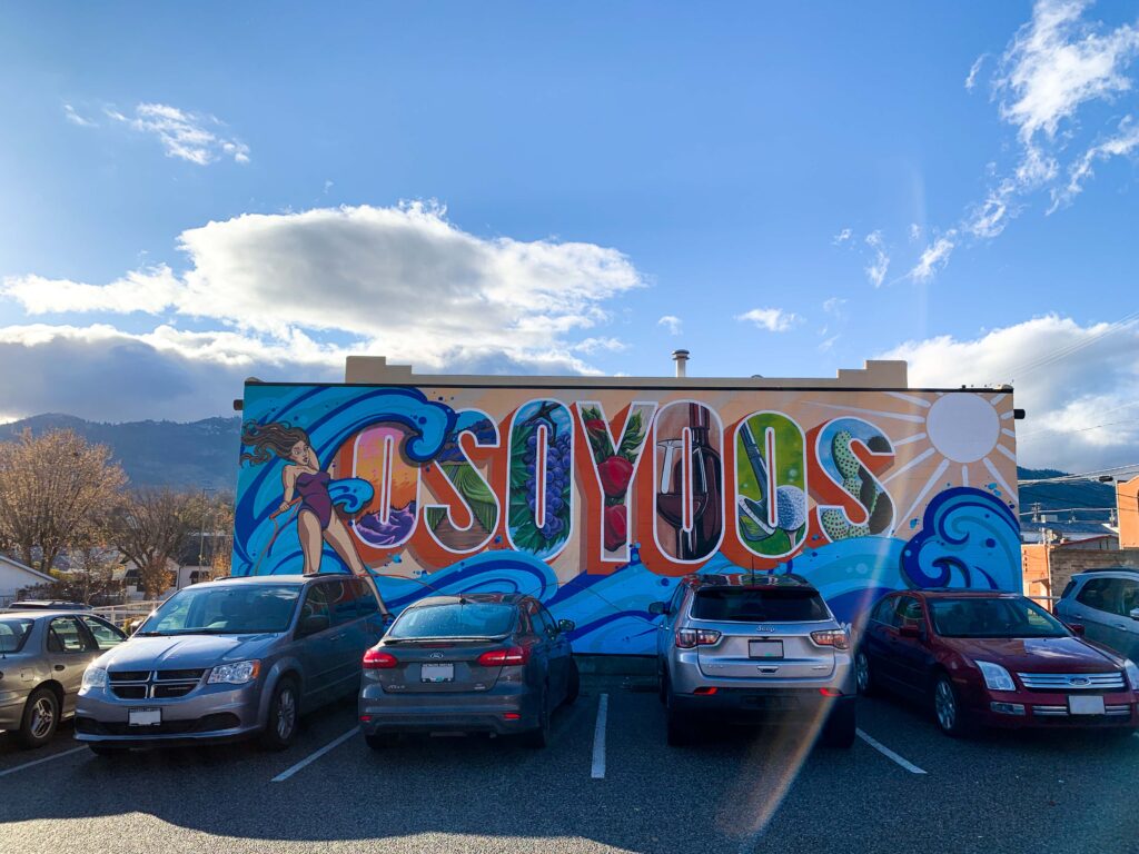 Mural of the word Osoyoos with cars parked nearby